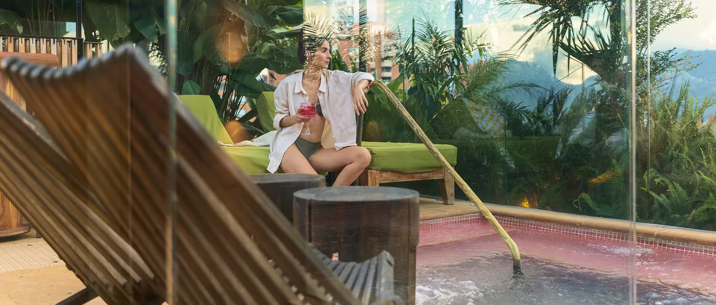 Mujer sentada en una silla frente a una piscina, disfrutando del ambiente relajante.