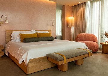 Habitación de hotel con una cama, una silla y una ventana iluminada.