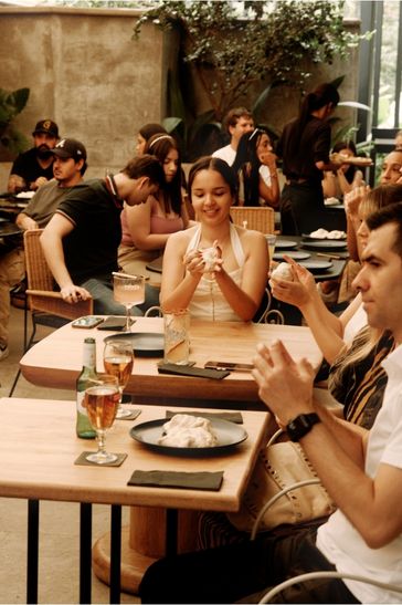 Diners at tables in a bustling restaurant, each with drinks, creating a vibrant social atmosphere