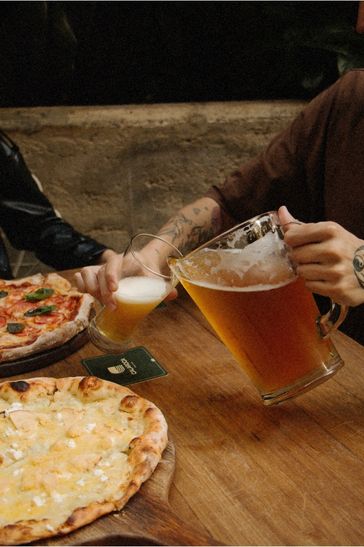 Dos personas levantando sus cervezas en un brindis, celebrando y compartiendo una alegre ocasión
