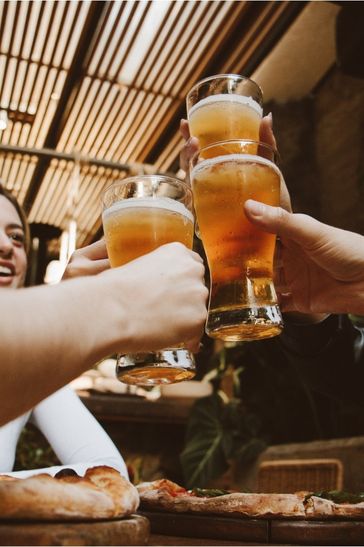 A group of three friends toasts with beer glasses at a table, enjoying a moment of camaraderie and celebration