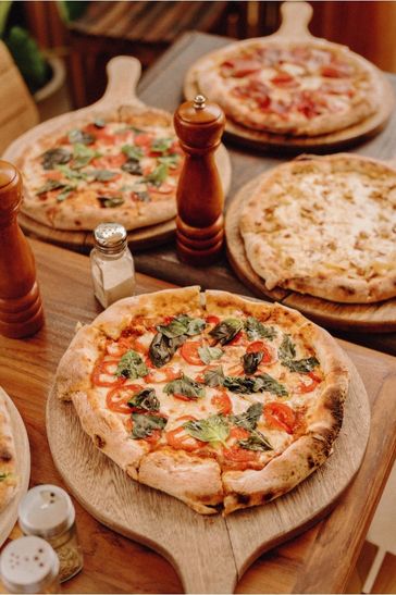 Pizza recién horneada servida en tablas de madera en un restaurante acogedor.