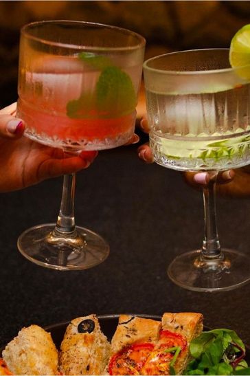 Dos personas con vasos de bebida y platos de comida, compartiendo un momento agradable