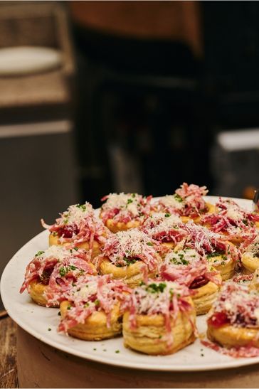 A dish displaying various meats and cheese, artistically presented on a white plate
