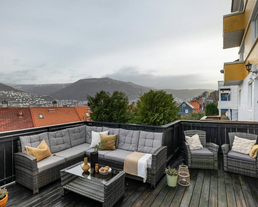 Balcón con muebles de mimbre y vista panorámica de las montañas al fondo.