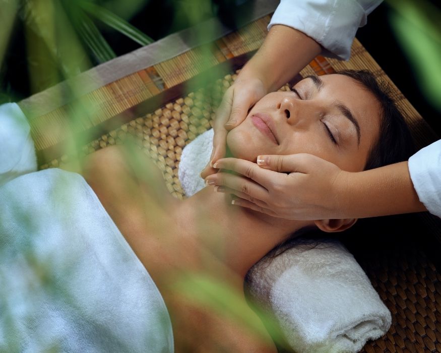 Mujer recibiendo un masaje facial en un spa, relajada y disfrutando de un tratamiento de belleza.