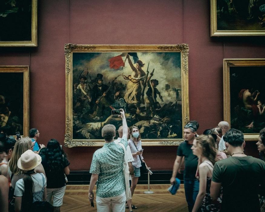 Personas tomando fotos de pinturas en un museo, capturando arte y cultura en un ambiente de admiración.