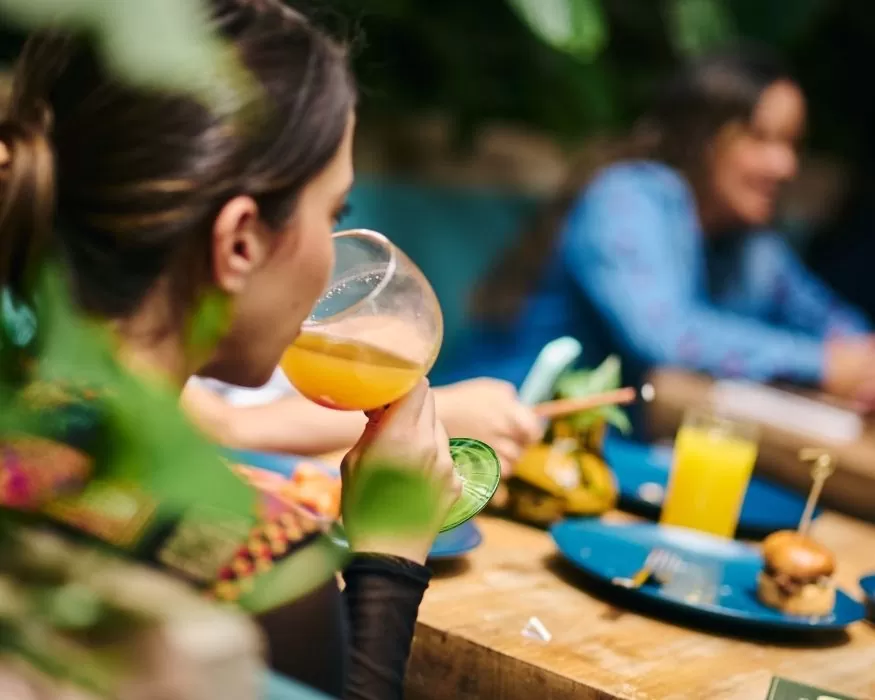 A woman drinks orange juice from a glass, appearing content and relaxed