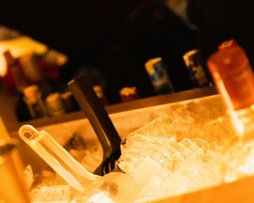 Un bar con hielo y varias botellas de alcohol dispuestas sobre la barra