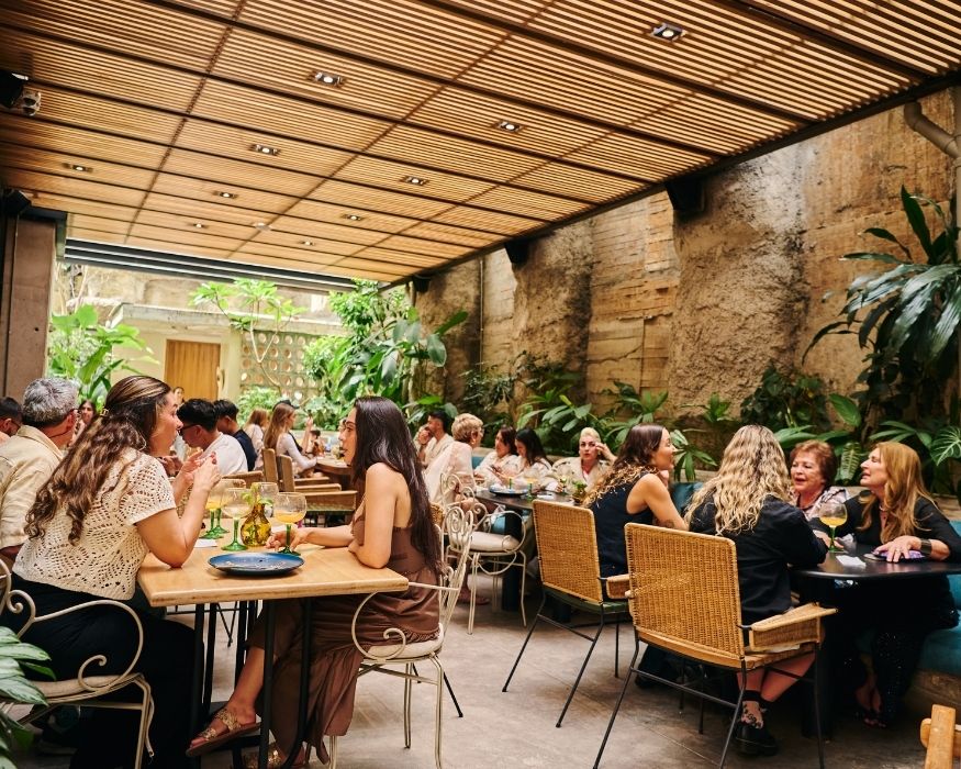 Gente disfrutando de su comida en un restaurante con plantas en el ambiente