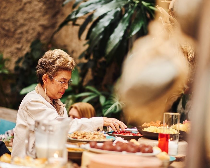 Una mujer está sirviendo alimentos en un buffet, mostrando una variedad de opciones para los comensales