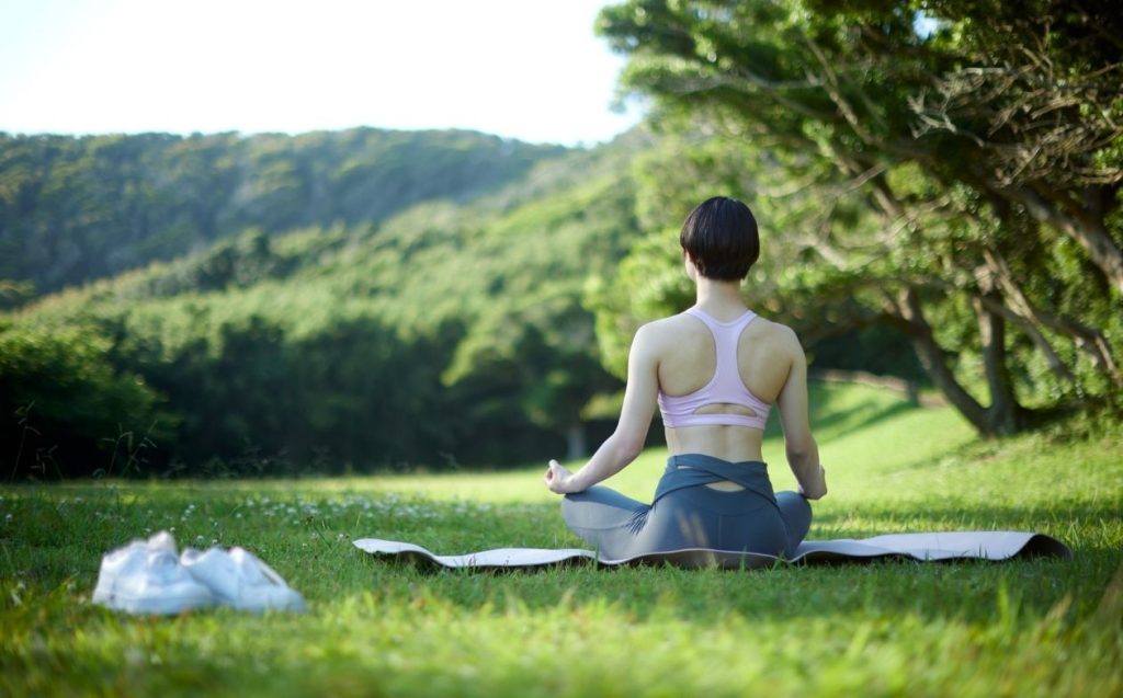 Amanece mujer sentada haciendo yoga en una esterilla sobre la hierba