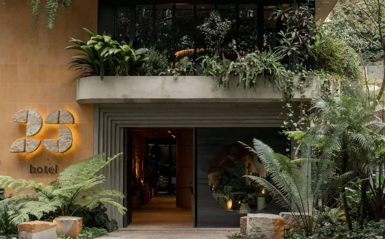 Entrada de 23hotel rodeada de plantas verdes y decorativas, creando un ambiente acogedor y natural