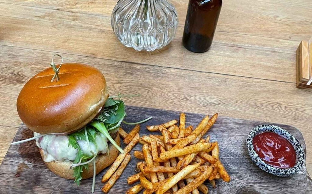 en cala roca una hamburguesa jugosa acompañada de papas fritas sobre una tabla de madera