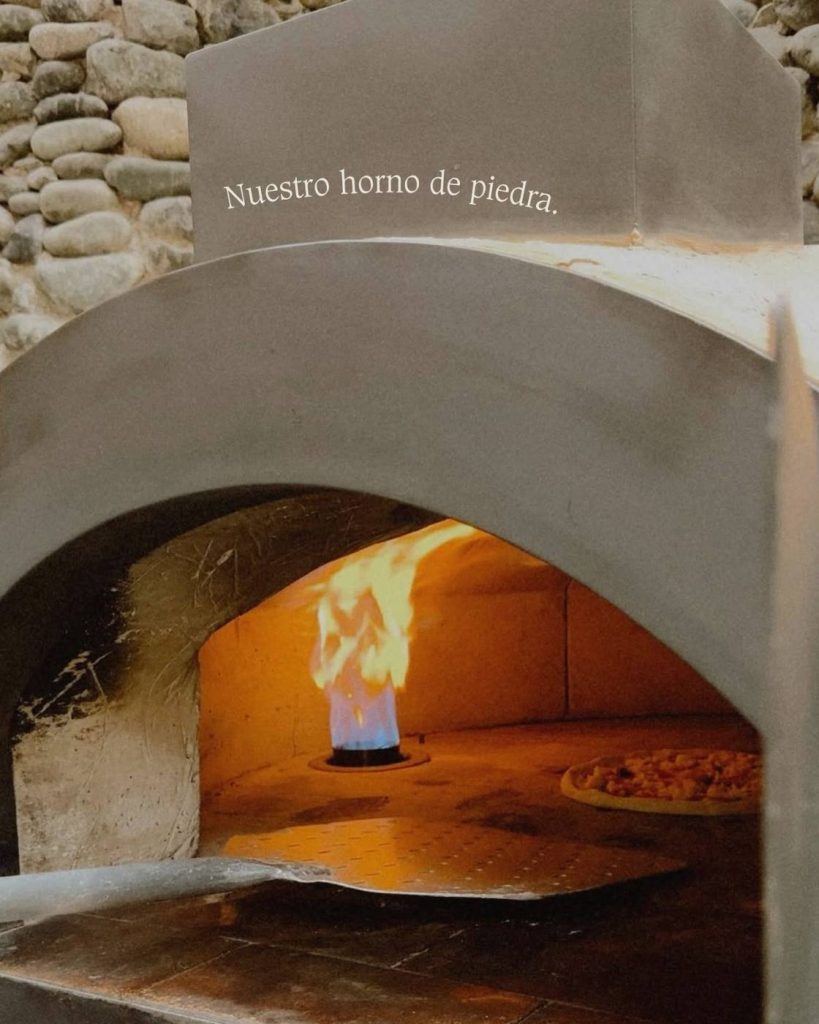 Pizza oven built of stone, with flames visible and a pizza cooking in your interior in cove rock