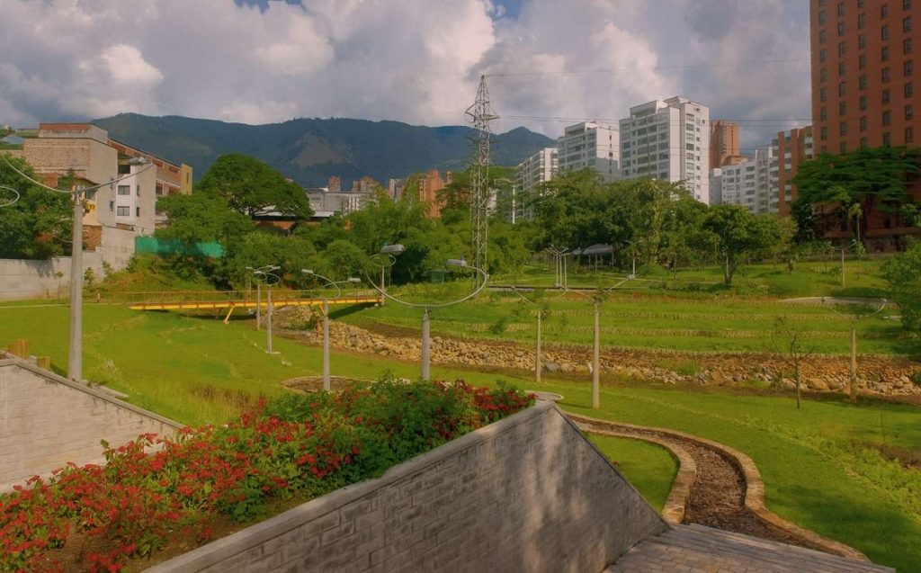 Park with a river and buildings in the background, ideal for yoga, meditation and walks near El Poblado.