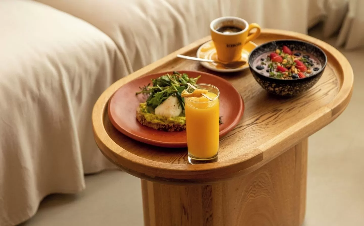 Mesa de madera con un tazón de frutas frescas y una taza de café humeante, creando un ambiente acogedor y cálido.