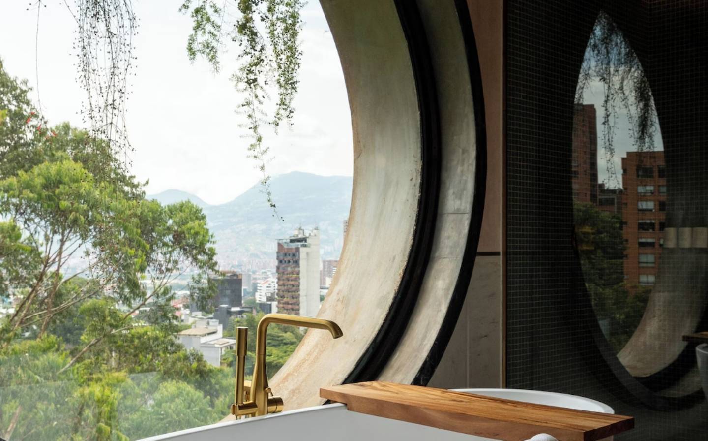 Baño elegante con una gran ventana redonda y una bañera, ideal para disfrutar de lujos al reservar con antelación.
