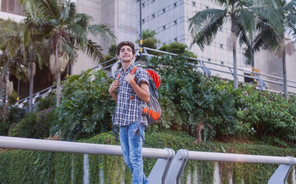 Young man with backpack standing on a bridge, ready for you to explore Medellin during a 3-day trip.