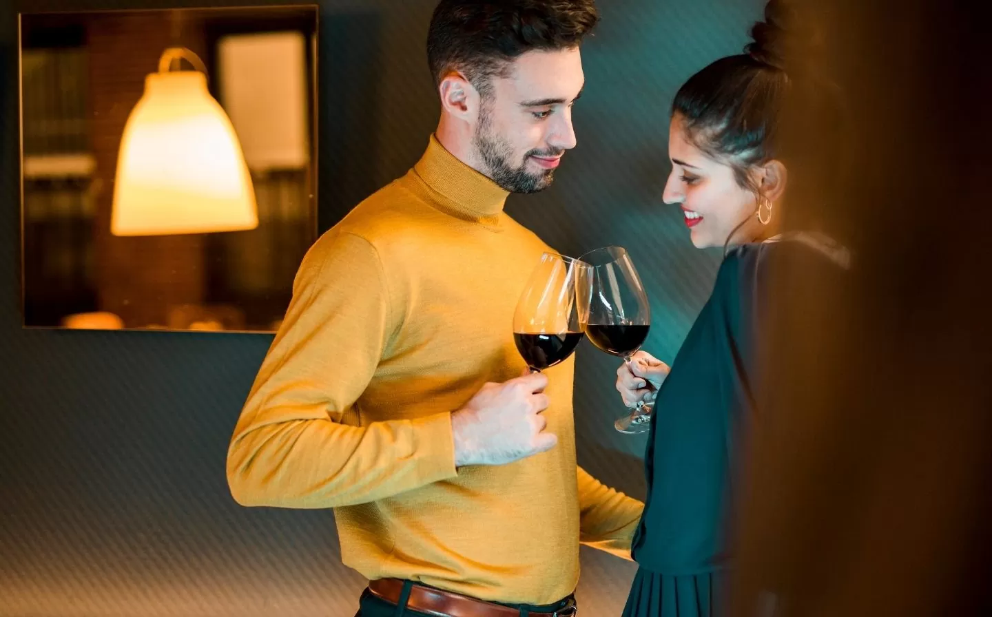 Un hombre y una mujer brindan con copas de vino, disfrutando de una cena gourmet en un restaurante cercano al hotel.