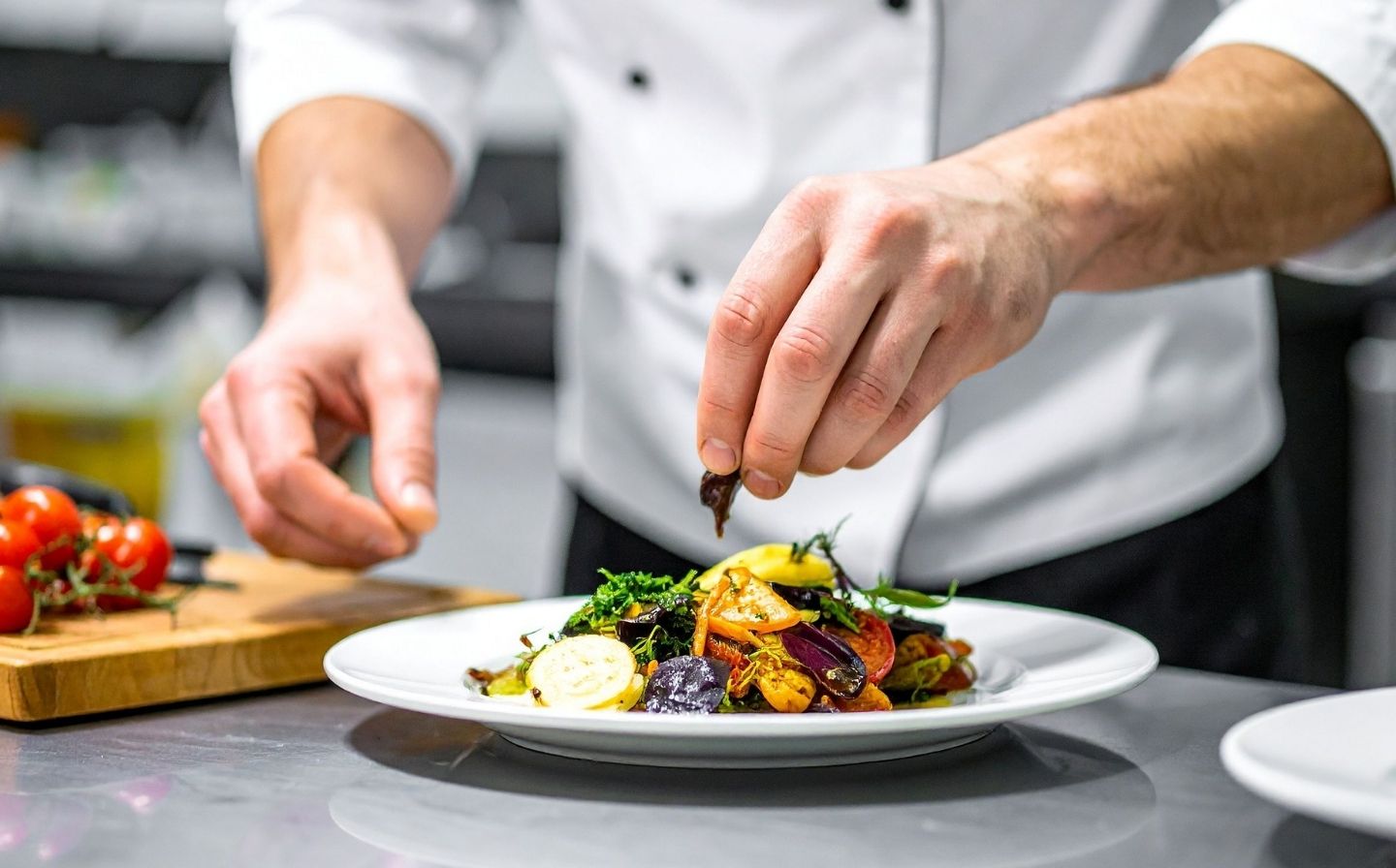 Chef preparando un plato gourmet en un restaurante, destacando la experiencia de cenas maridaje cerca del hotel.