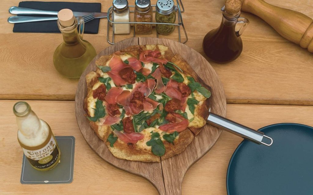 A freshly baked pizza sits on a wooden cutting board, ready to be sliced and served