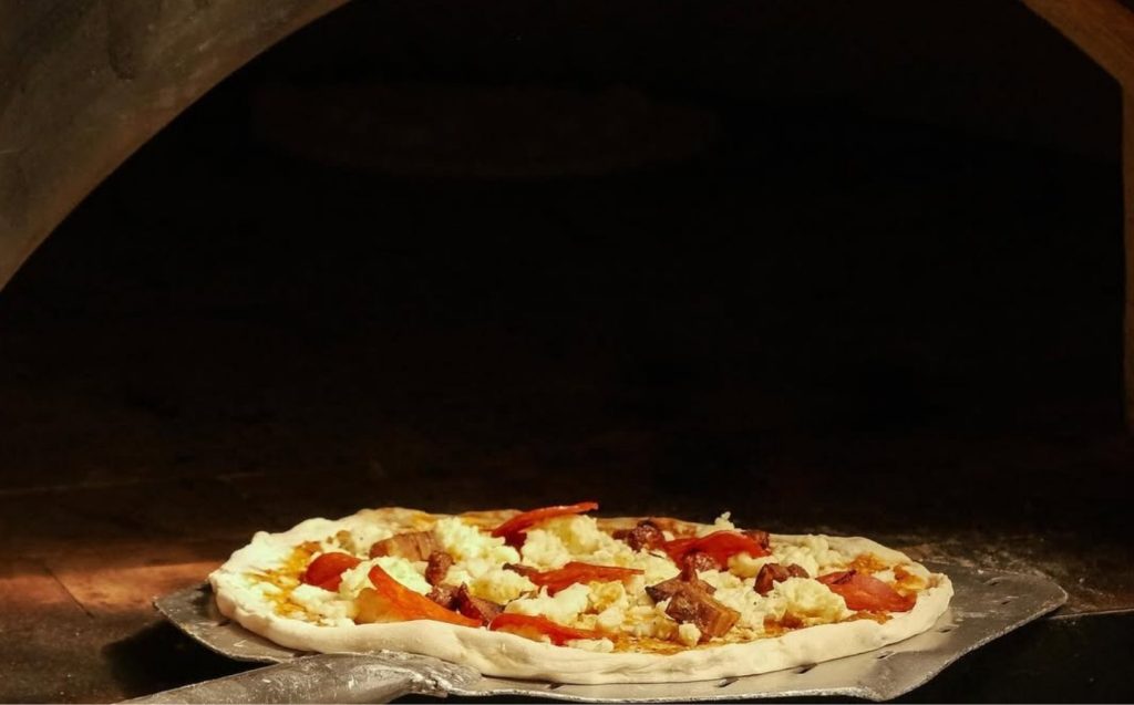 A delicious pizza is baking in a hot oven, with melted cheese bubbling and crust turning golden brown