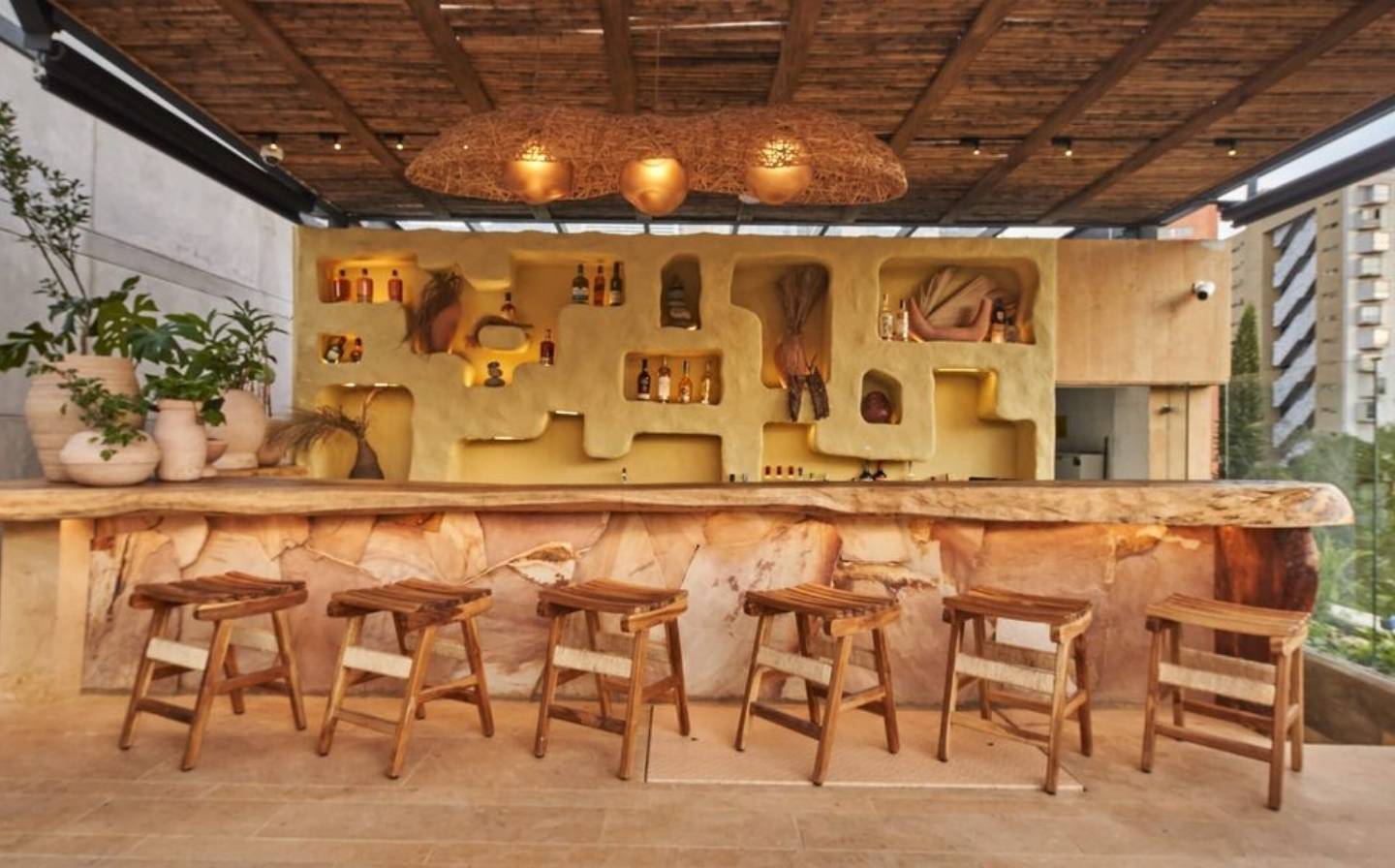 Bar con taburetes de madera y un amplio mostrador de madera, ideal para disfrutar en terrazas de hoteles