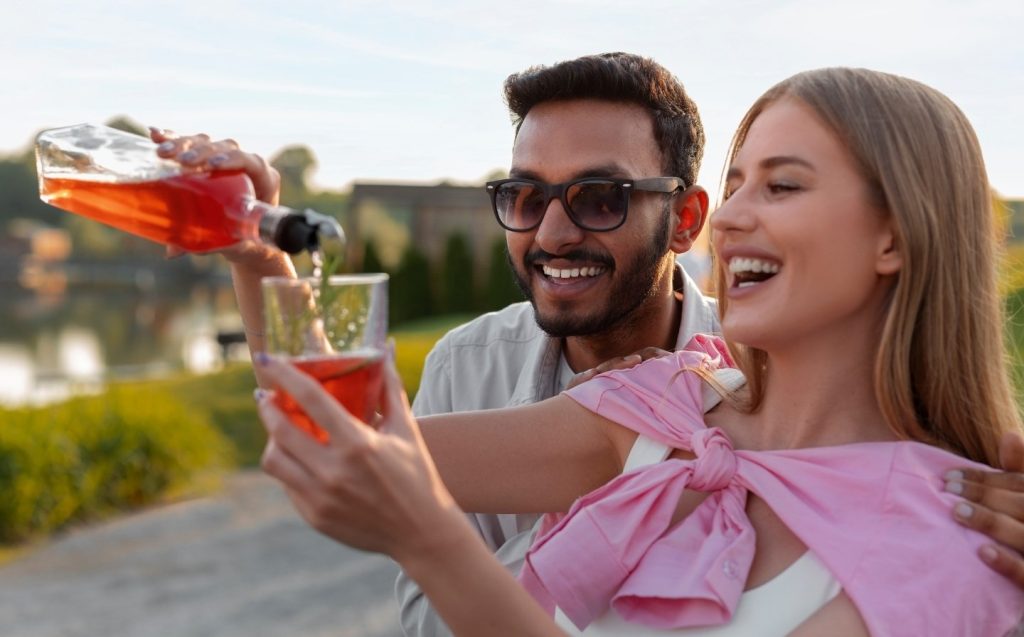Smiling man and woman holding wine glasses, enjoying a romantic dinner with lovely views.