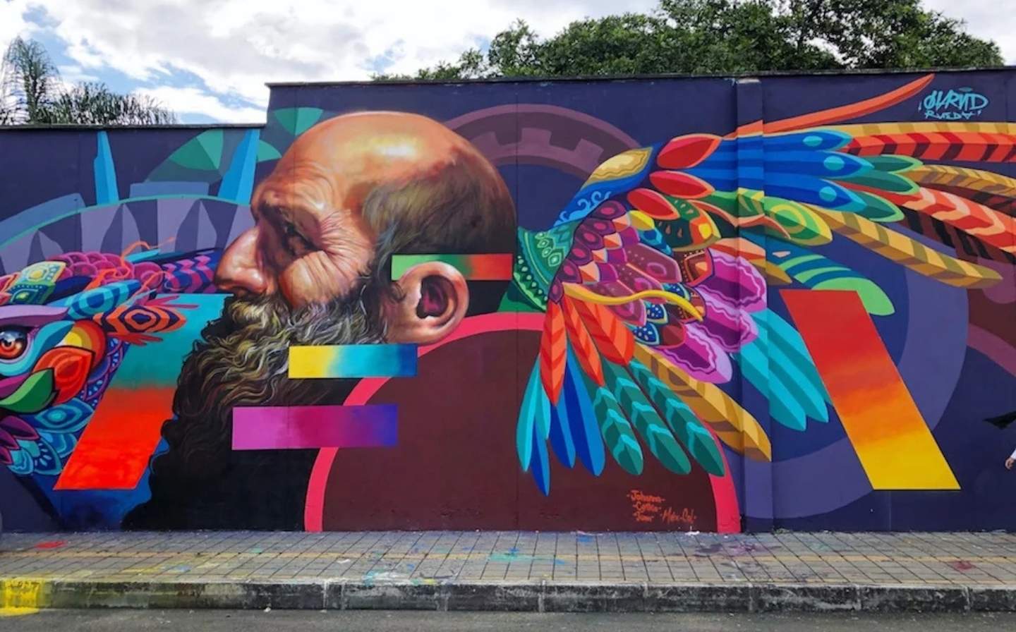 Mural colorido de un hombre con un pájaro posado en su cabeza, lleno de vida y creatividad