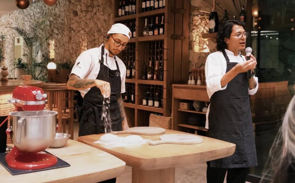 Two chefs prepare food in a restaurant kitchen, focused on making a delicious vegan pizza