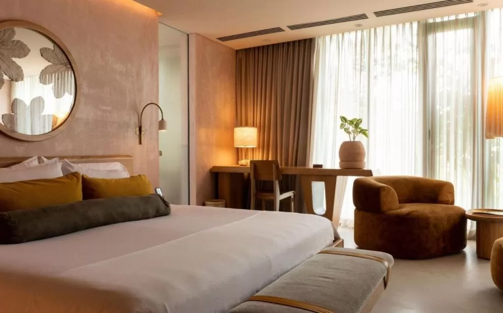 Habitación ideal en 23 Hotel, con una cama grande y un espejo redondo que añade elegancia al espacio.