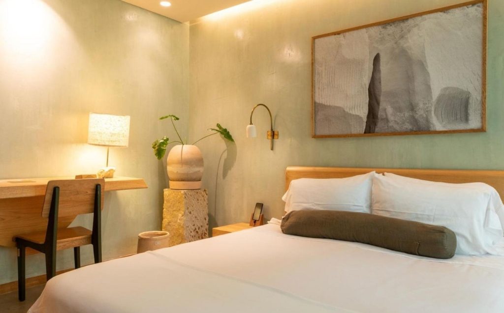 Ideal room in Hotel 23 with bed, desk and a decorative painting on the wall.