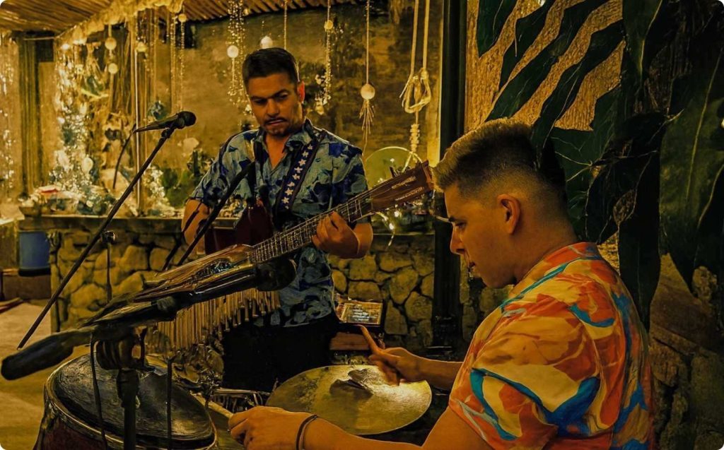 Two men playing guitar and singing at a restaurant during a monthly cultural event in El Poblado.