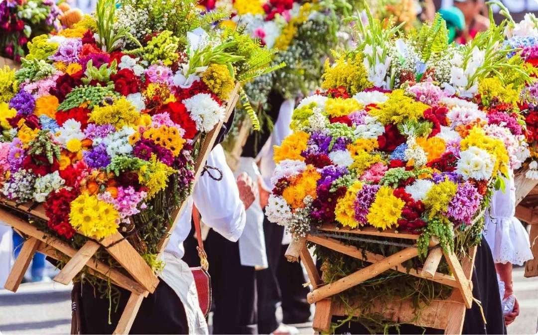 Personas llevando flores por la calle durante los Festivales culturales de Medellín